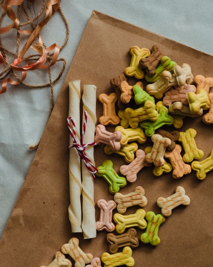 About A vibrant assortment of bone-shaped dog treats displayed on brown paper, perfect for pets.